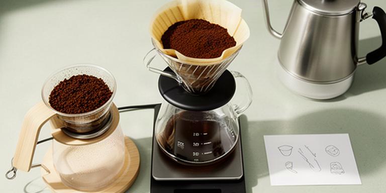 Digitale Waage unter einem Pour-Over-Filter mit Kaffeekanne und handschriftlichen Brühdaten